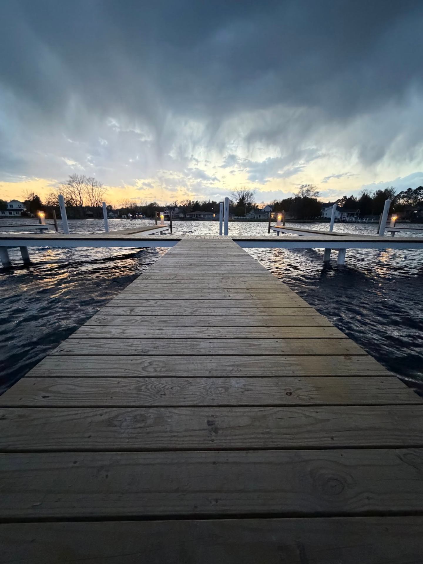 Wood pier extending into Smith Bayou under a dramatic sunset sky at Cottage Shores